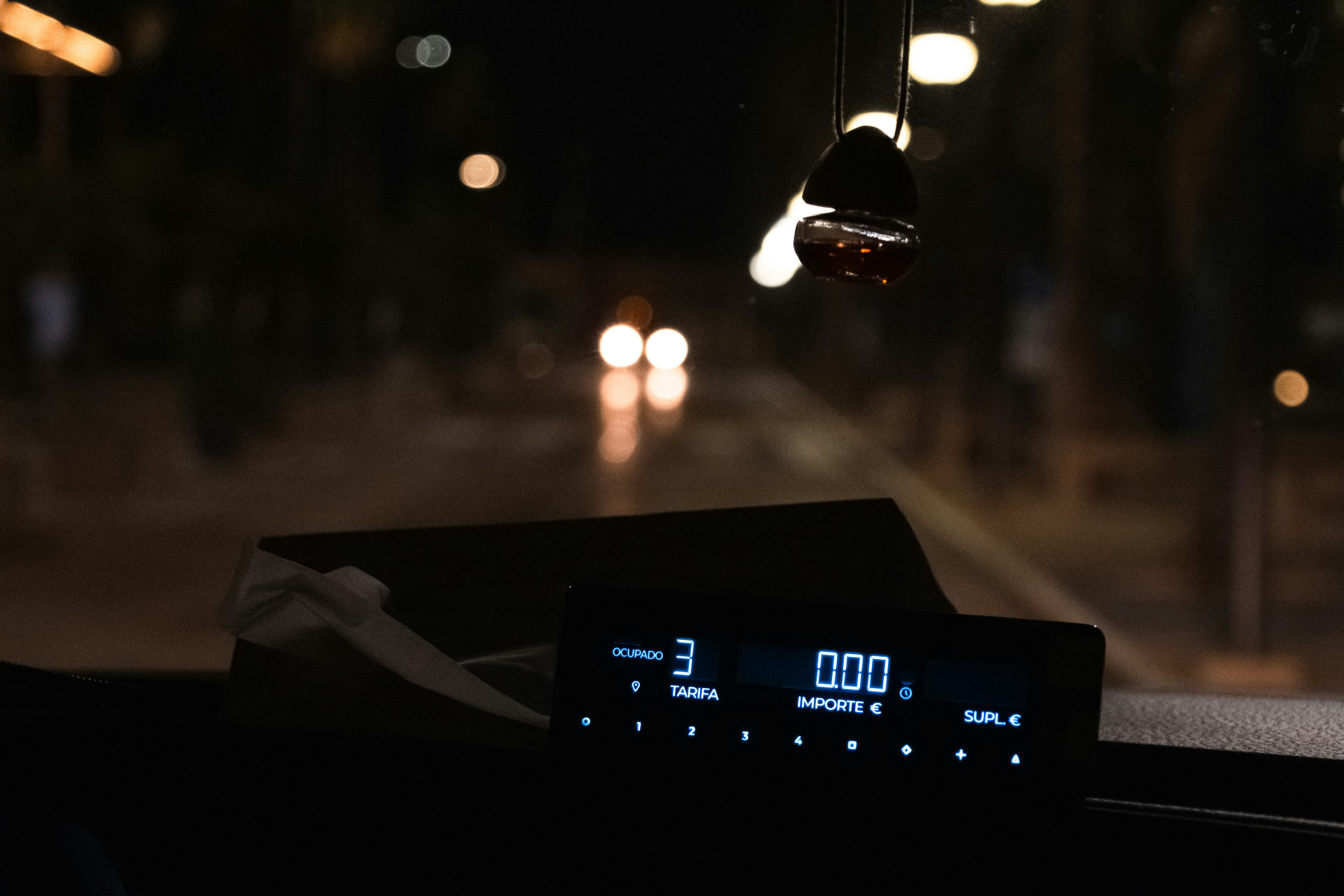 Inside a Barcelona taxi, with the meter showing €0 in sharp focus while traffic and cars blur outside the window.